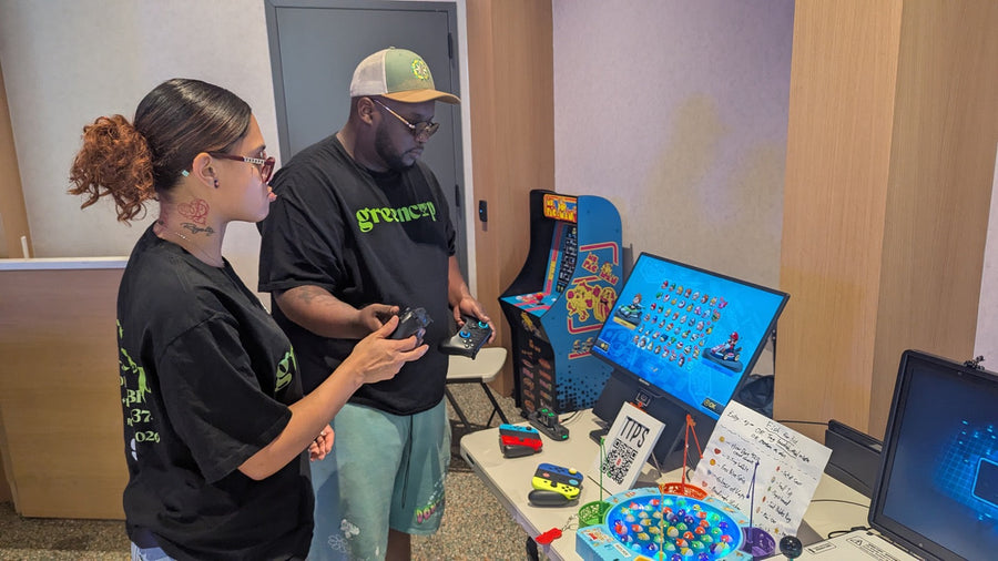 Two guests with controllers beside the fishing prize game at the GreenCup x Budcade pop-up