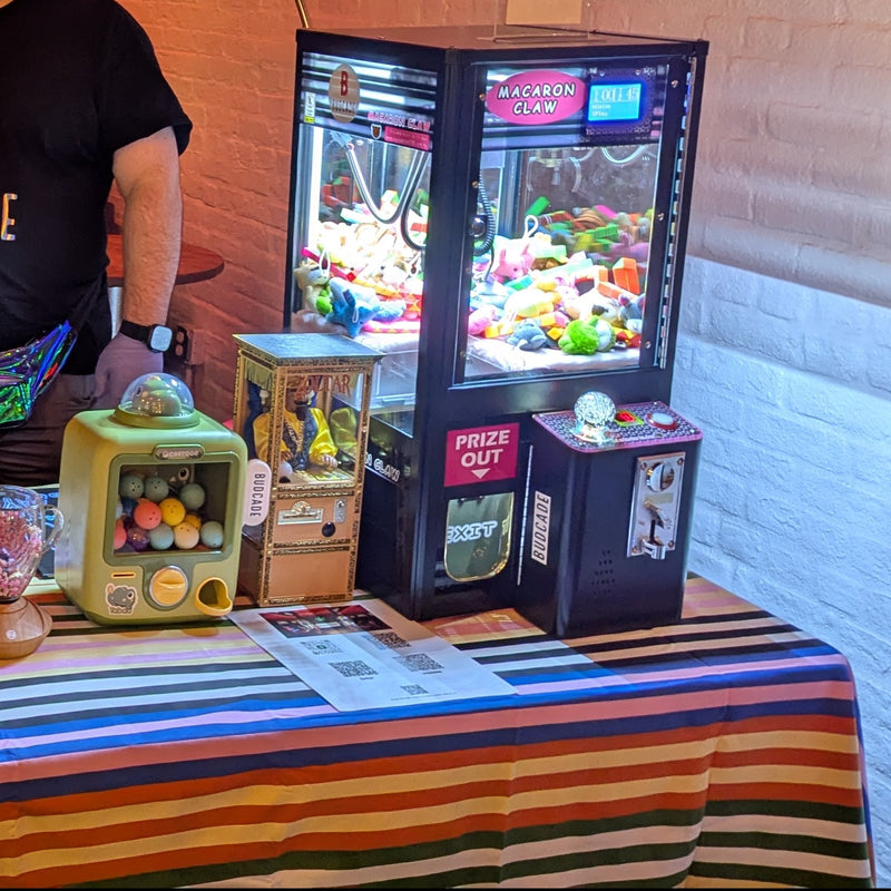 Budcade claw machine and tabletop prize games set up at an event