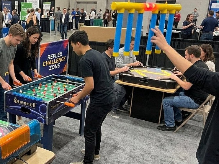 Adults playing foosball and a reflex game at a game station