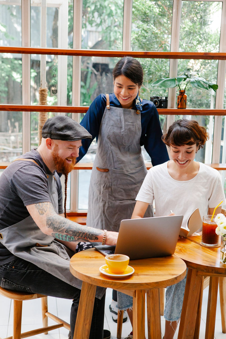 A cafe team in aprons smiling at a laptop together