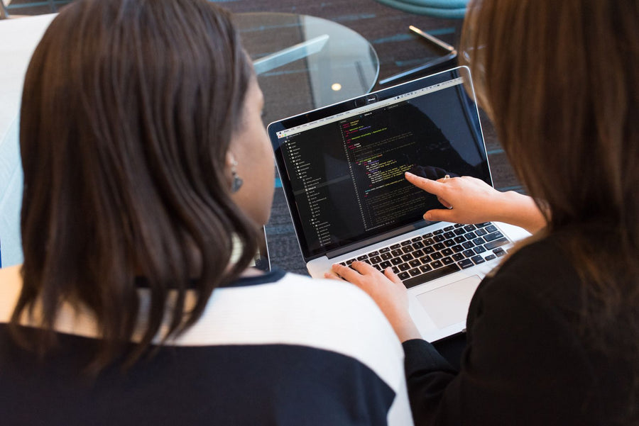 Two women going over code together on a laptop