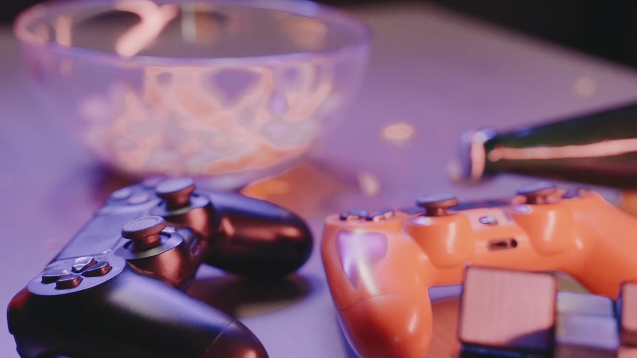 Game controllers and snacks on a table under purple light